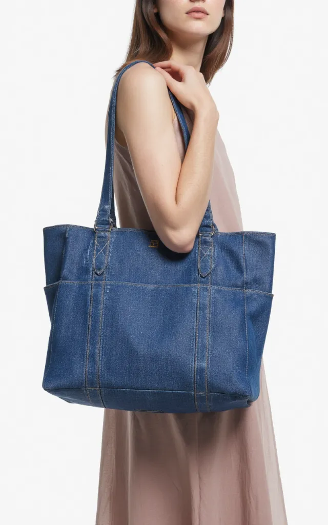A French female model with a Denim bag, wearing a dress, against a white background, in a front   facing close   up